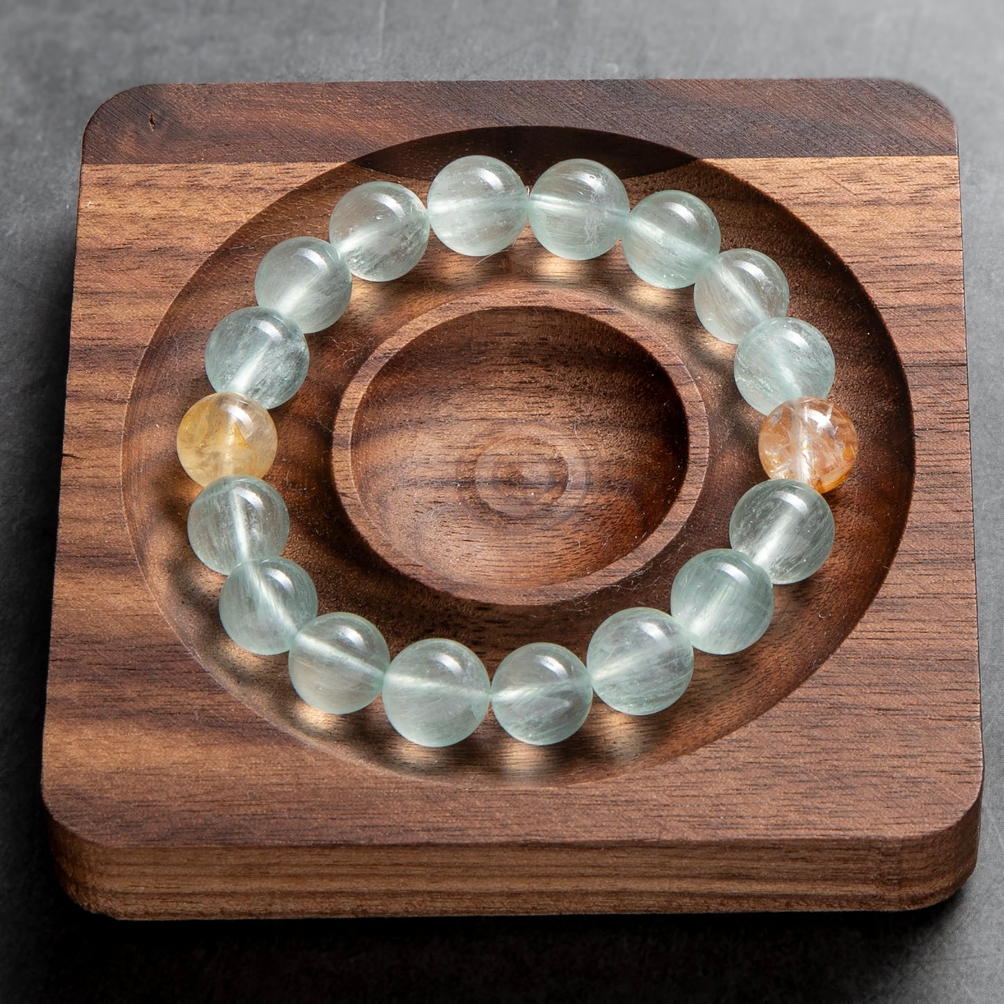 Glowing crystal bracelet on a wooden stand with a gray background