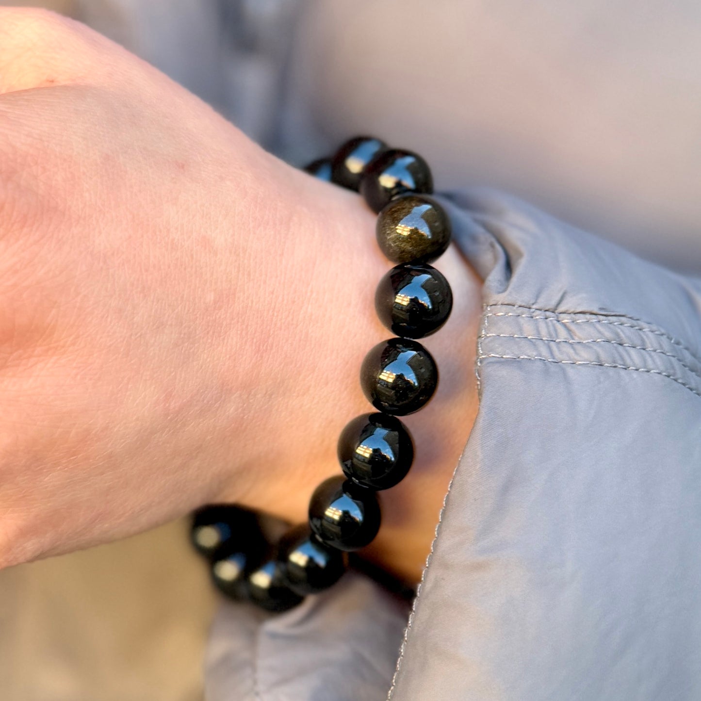 Black beaded bracelet on a wrist with a blurred background