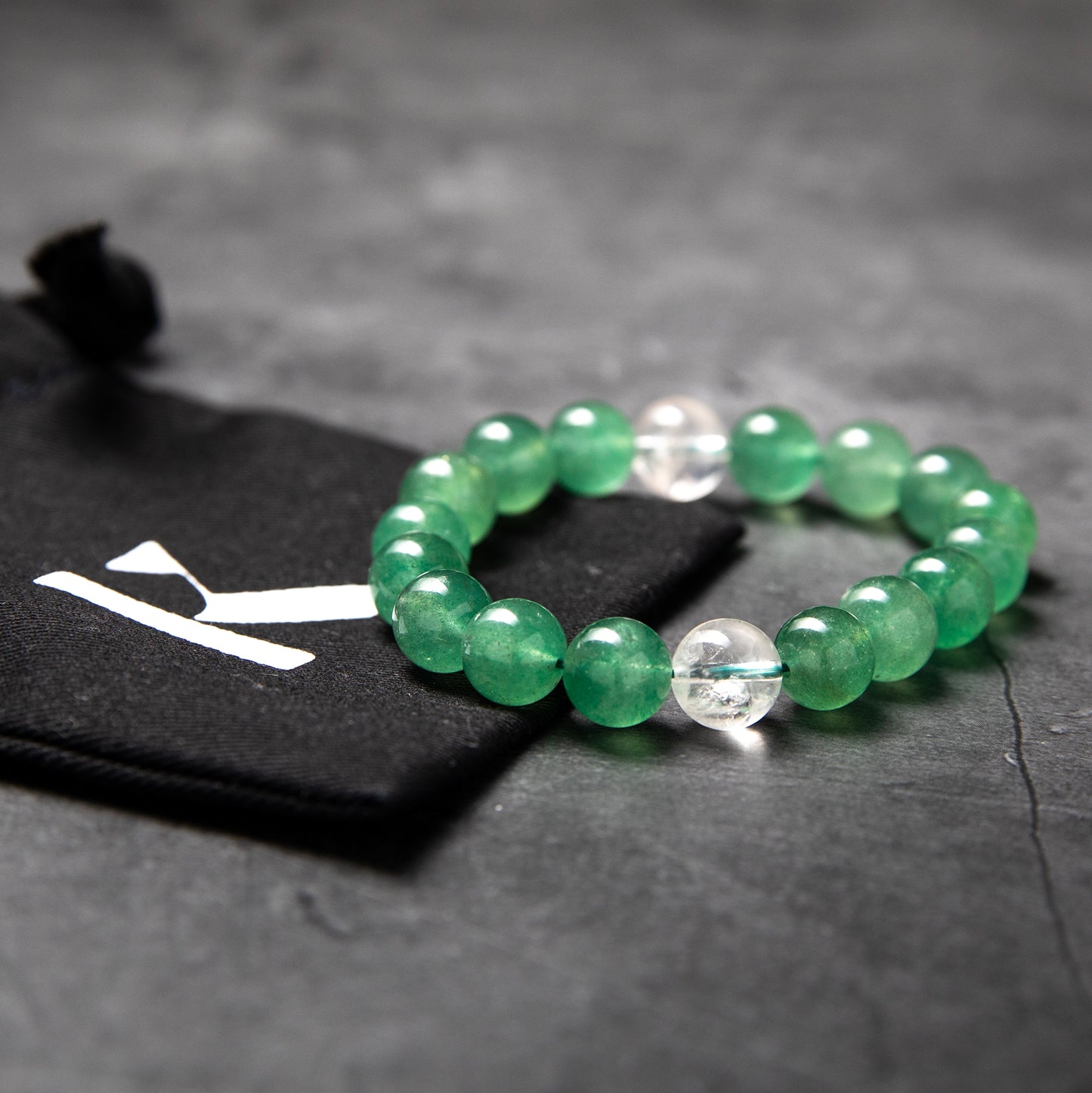Green beaded bracelet on a dark surface with a blurred background