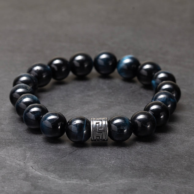Black beaded bracelet with a silver clasp on a gray surface