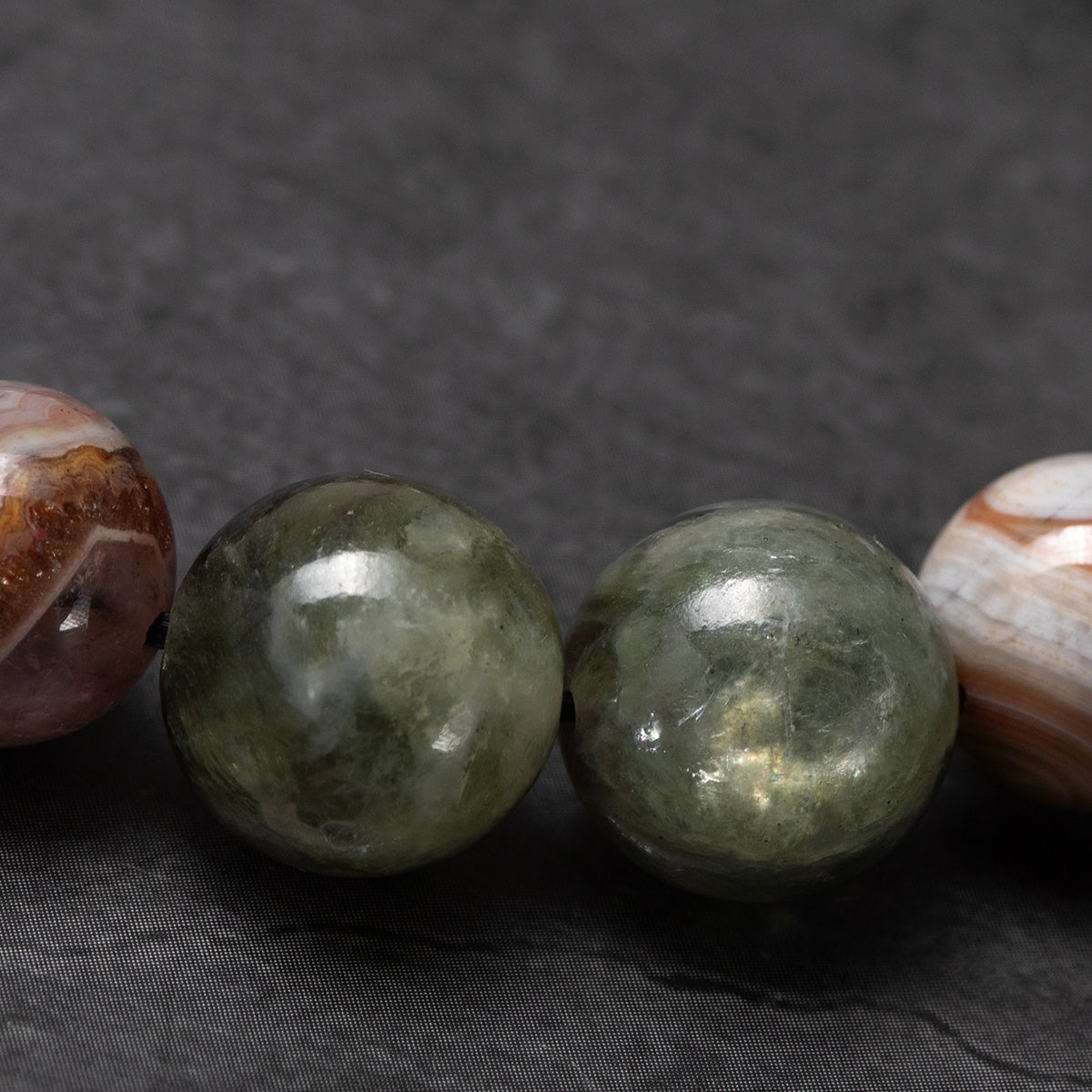 Close-up of three polished gemstones on a dark fabric background