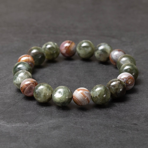 Beaded bracelet with green and brown stones on a dark gray background