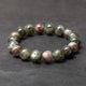 Beaded bracelet with green and brown stones on a dark gray background