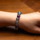 Close-up of a wrist wearing a bracelet with purple and gray beads on a wooden surface