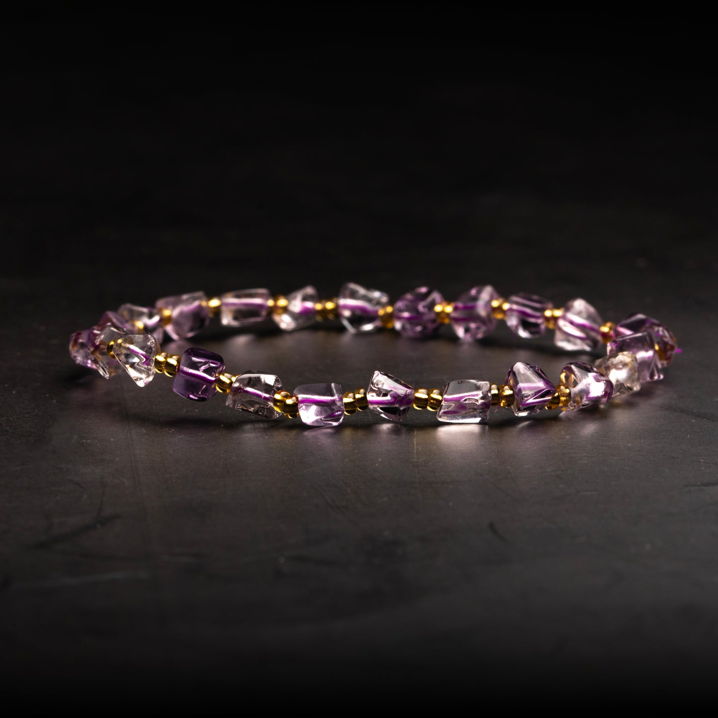 Beaded bracelet with purple and gold accents on a dark background