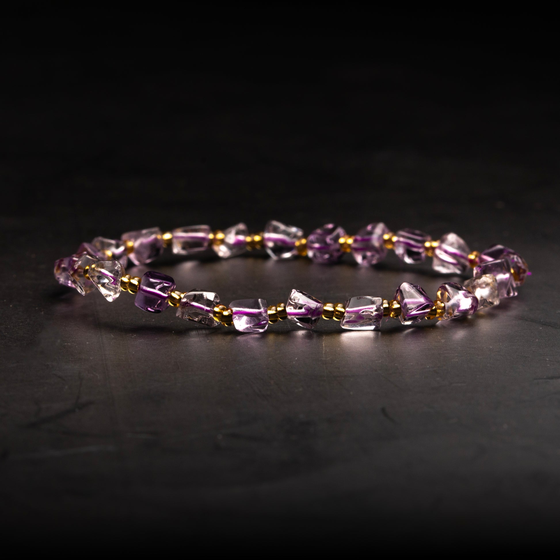 Beaded bracelet with purple and gold accents on a dark background