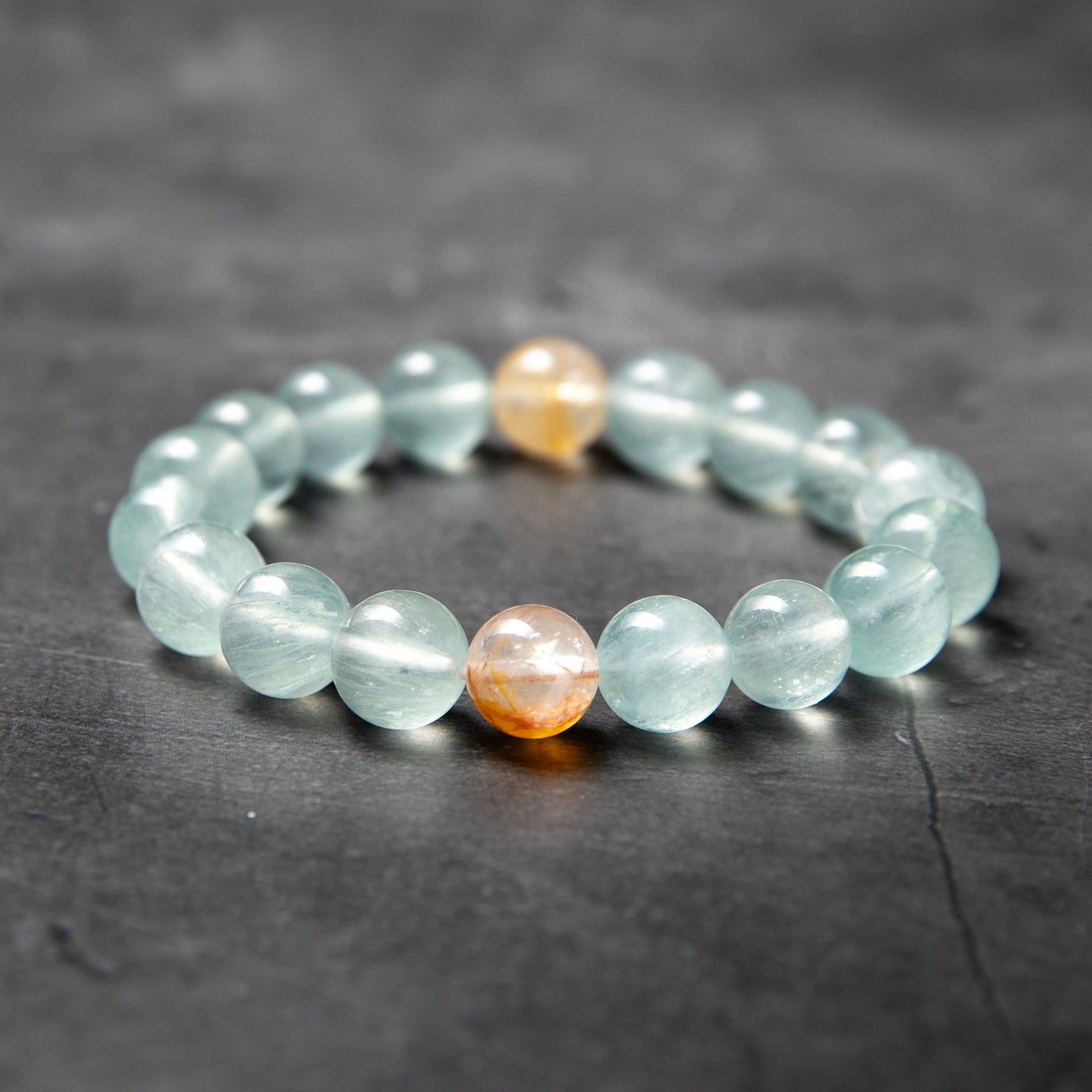 Beaded bracelet with light blue and orange beads on a dark surface