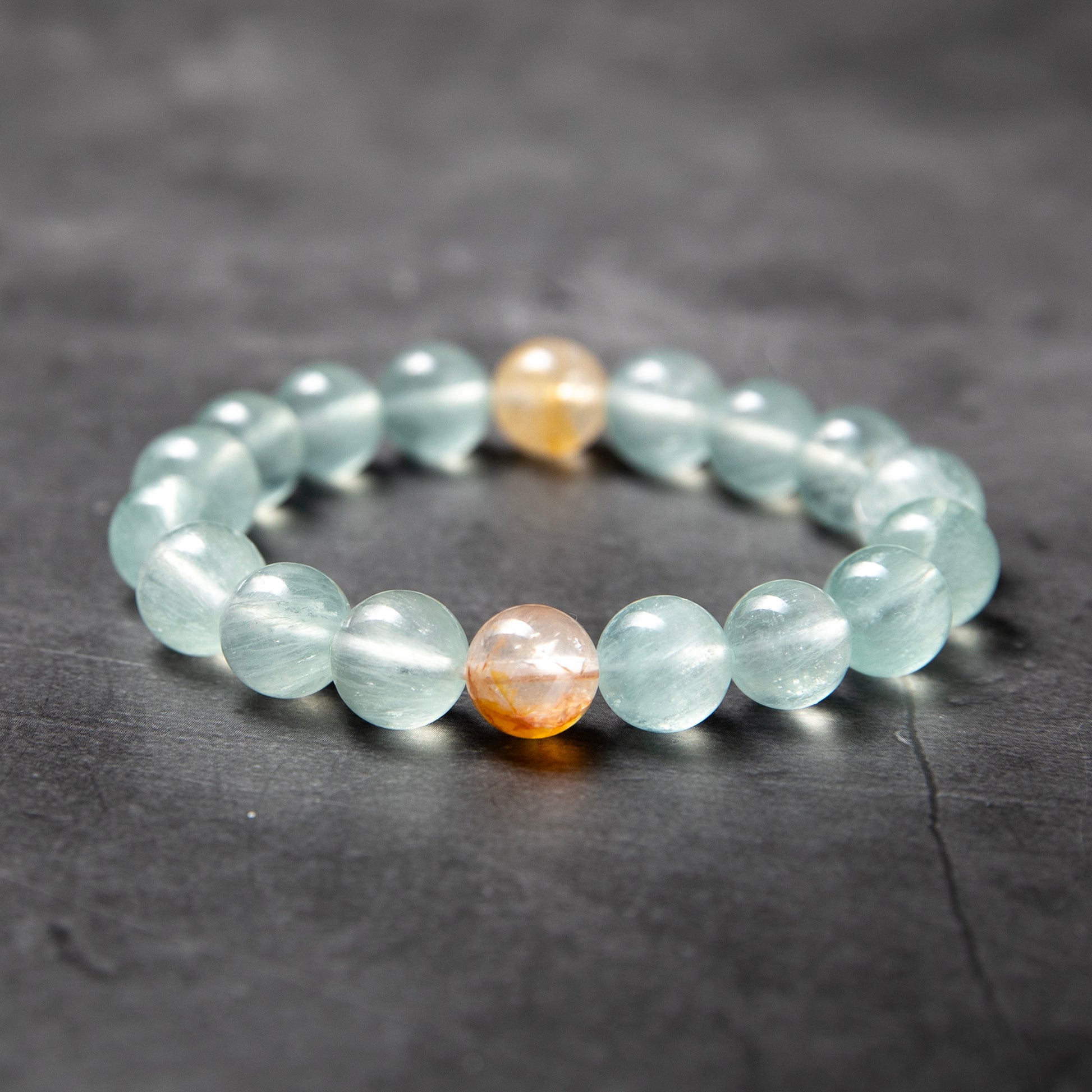 Beaded bracelet with light blue and orange beads on a dark surface