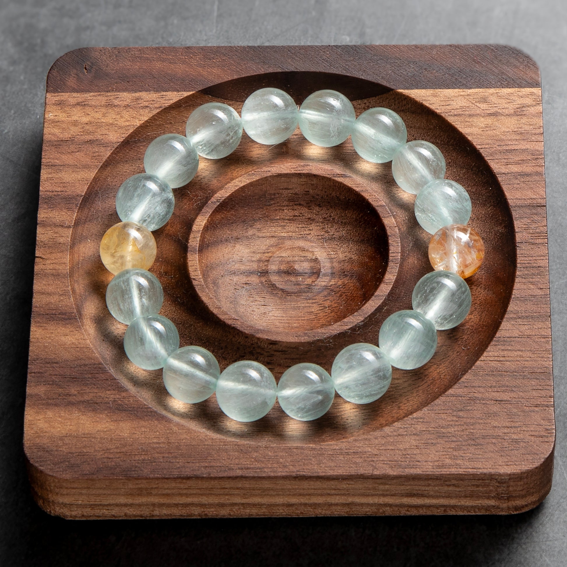 Glowing crystal bracelet on a wooden stand with a gray background