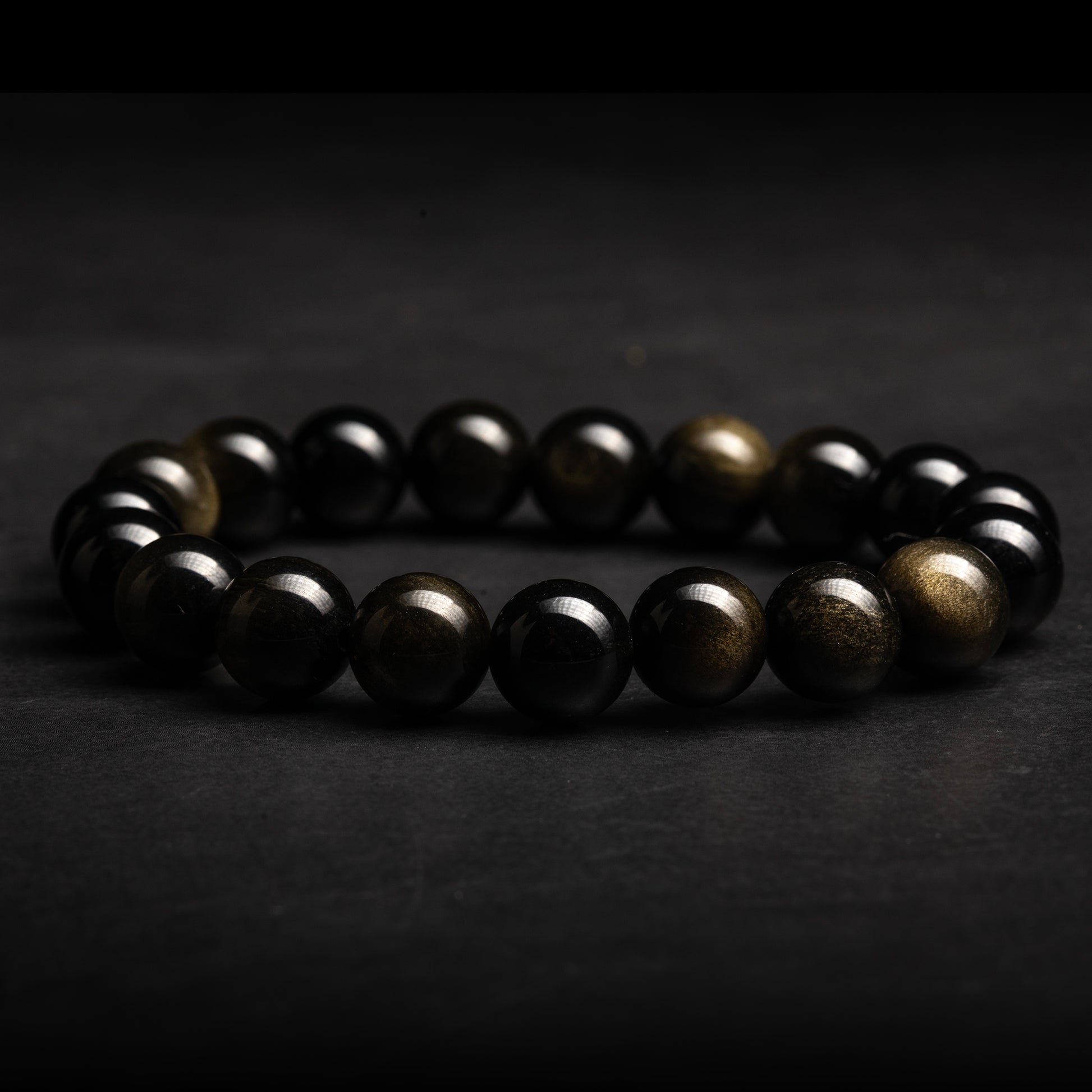 Black and gold beaded obsidian bracelet on a dark background