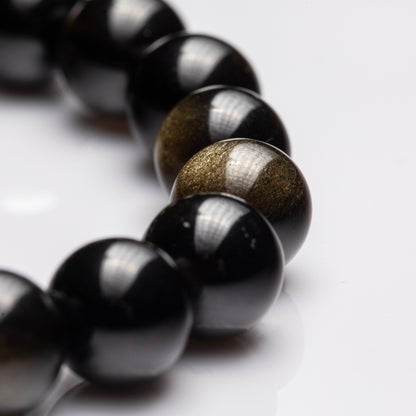Close-up of a bracelet with black and gold beads on a light background