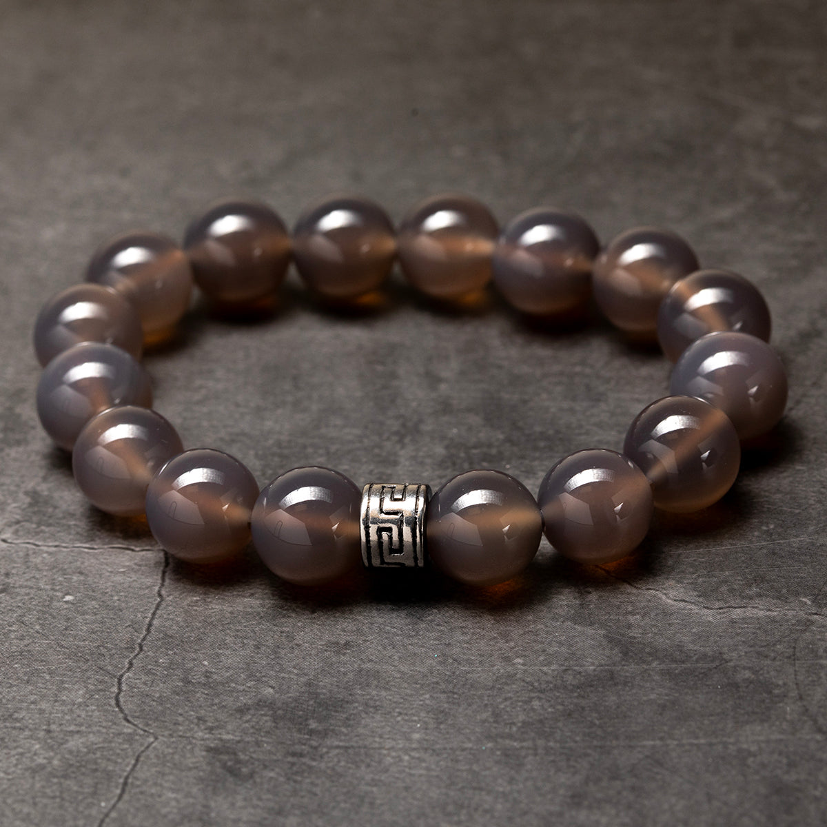 Brown beaded bracelet with a silver clasp on a dark stone surface