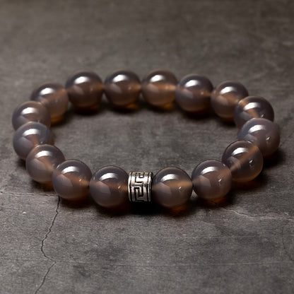 Brown beaded bracelet with a silver clasp on a dark stone surface