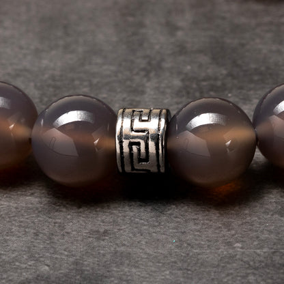 grey agate beaded bracelet with a stainless steel piece on a dark background