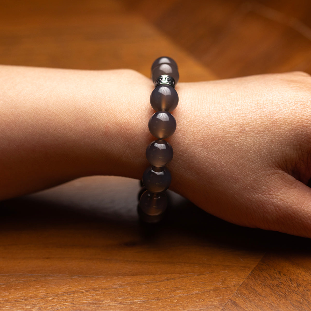 Black beaded bracelet on a wrist against a wooden background