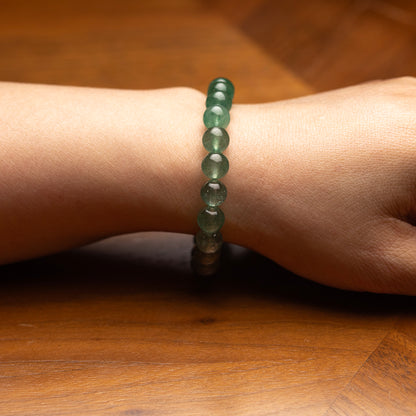 Green beaded bracelet on a wrist against a wooden background