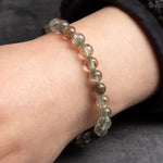 Close-up of a wrist wearing a bracelet with clear beads on a neutral background