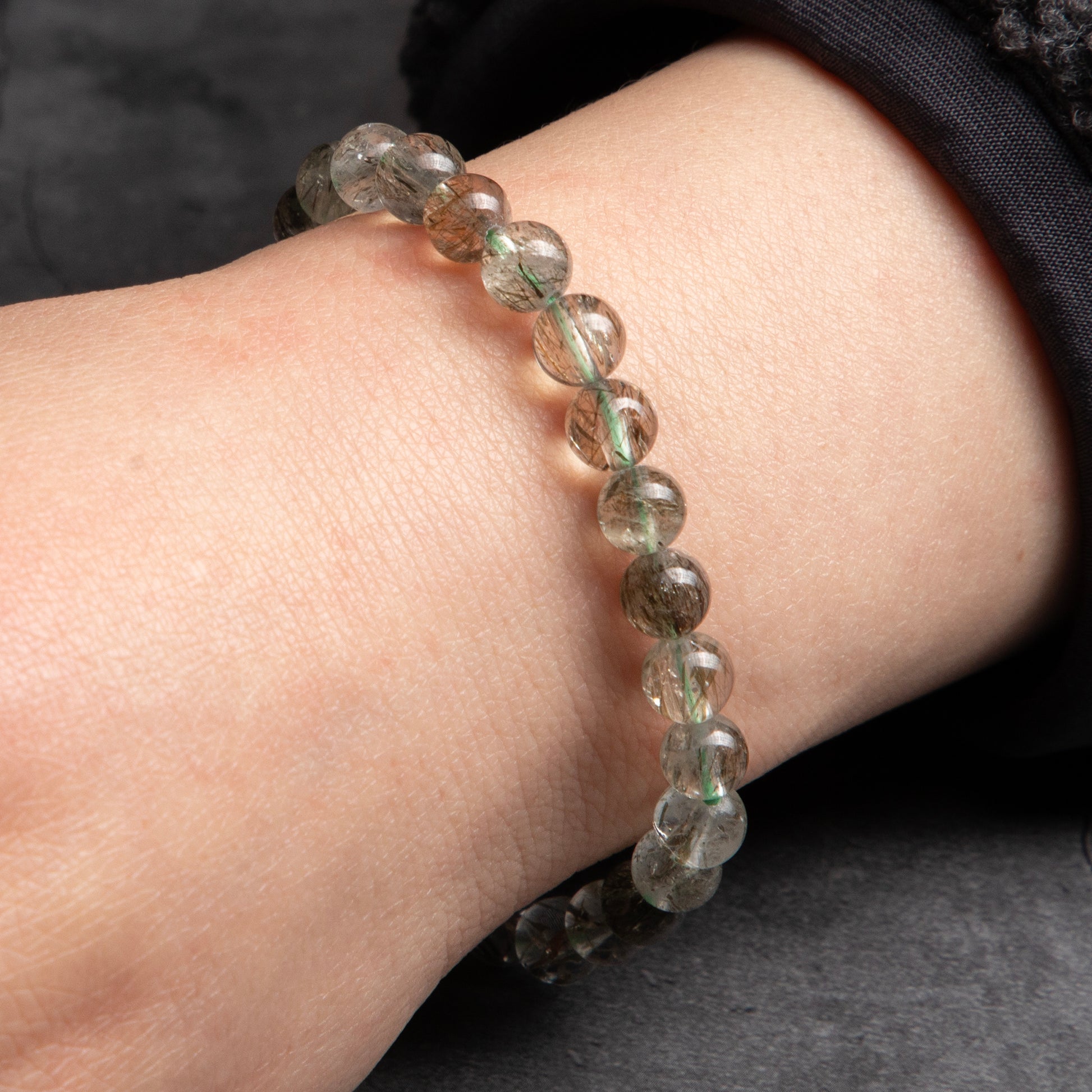 Close-up of a wrist wearing a bracelet with clear beads on a neutral background