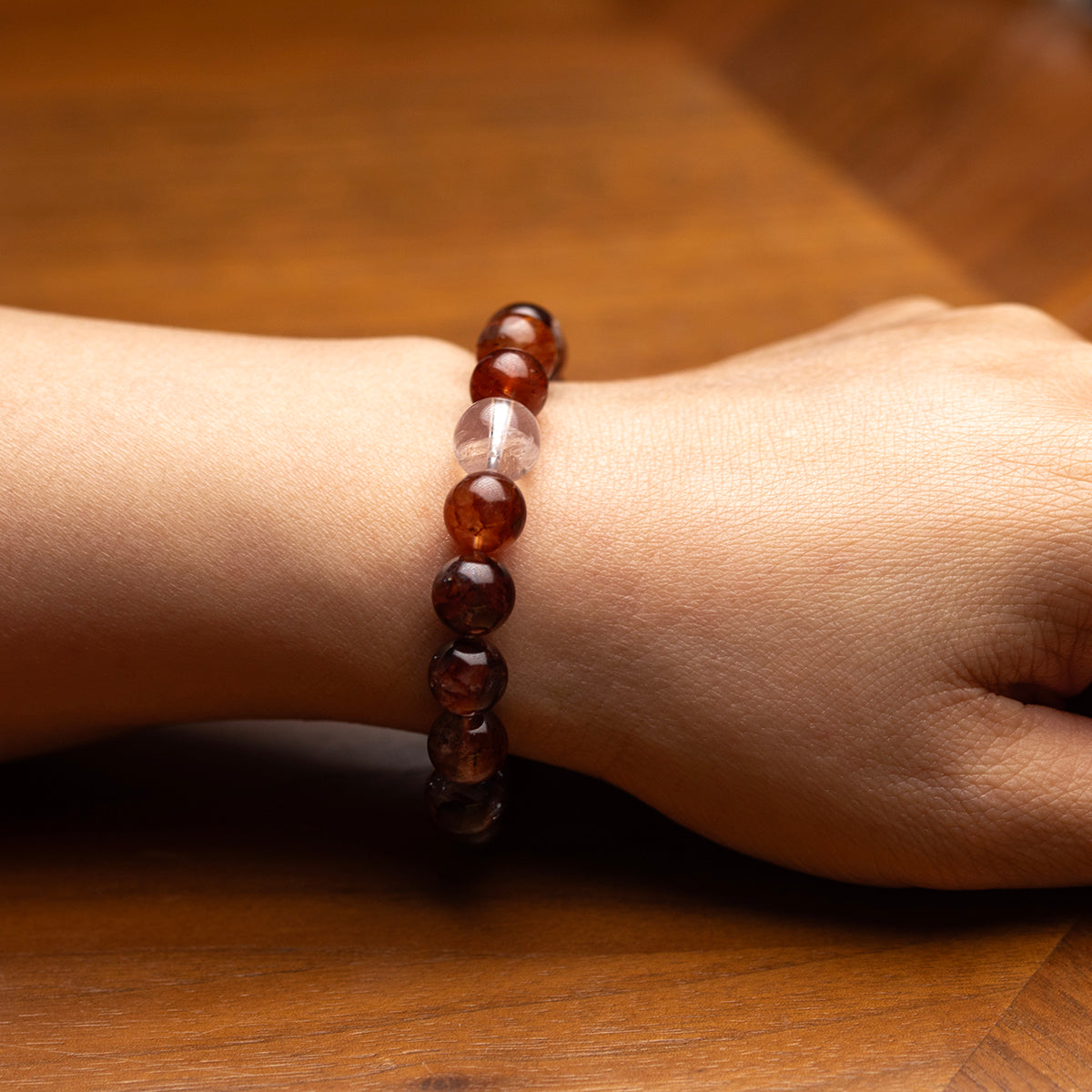 Close-up of a wrist wearing a beaded bracelet on a wooden surface