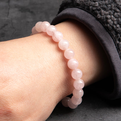 Rose quartz bracelet on a wrist against a dark background