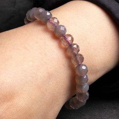 Purple beaded bracelet on a wrist against a dark background
