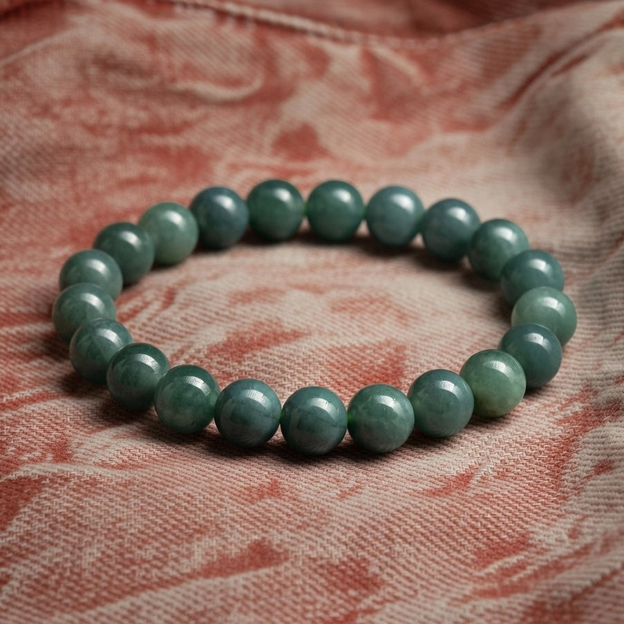 a green bracelet on a coral and sand coloured piece of denim