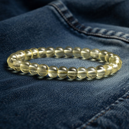 a yellow beaded bracelet rests on folded denim