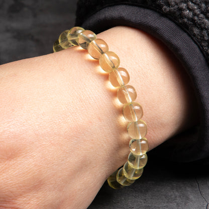 Close-up of a wrist wearing a bracelet with clear beads on a dark background
