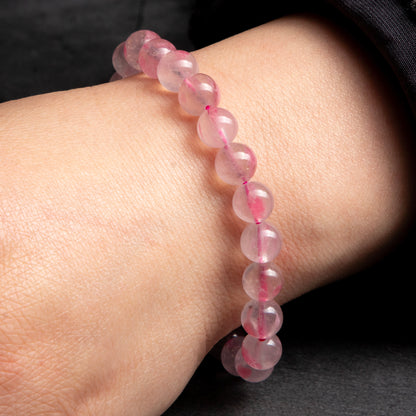 Pink beaded bracelet on a wrist against a dark background