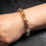 Close-up of a wrist wearing a beaded bracelet on a dark background