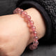 Pink beaded bracelet on a wrist against a dark background