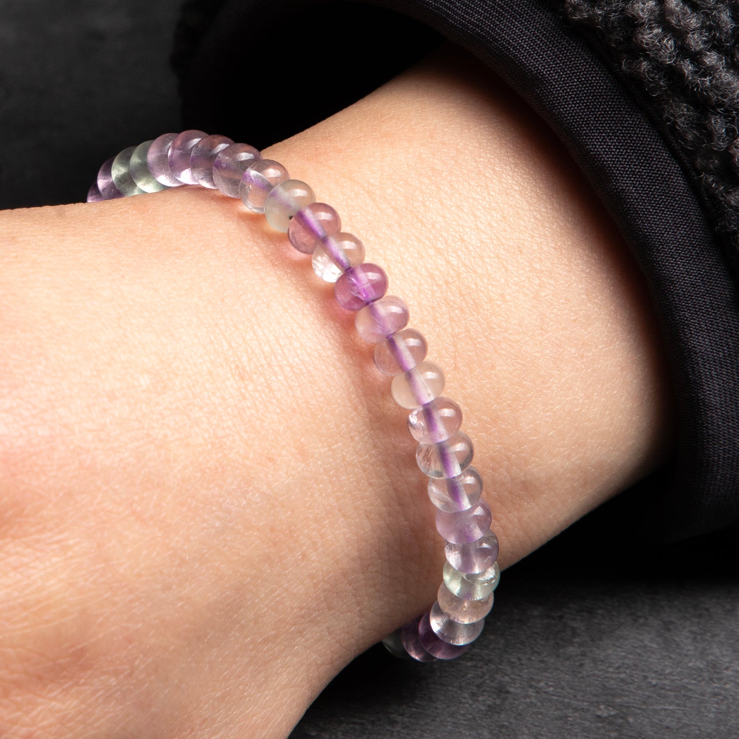Multicolored beaded bracelet on a wrist against a dark background