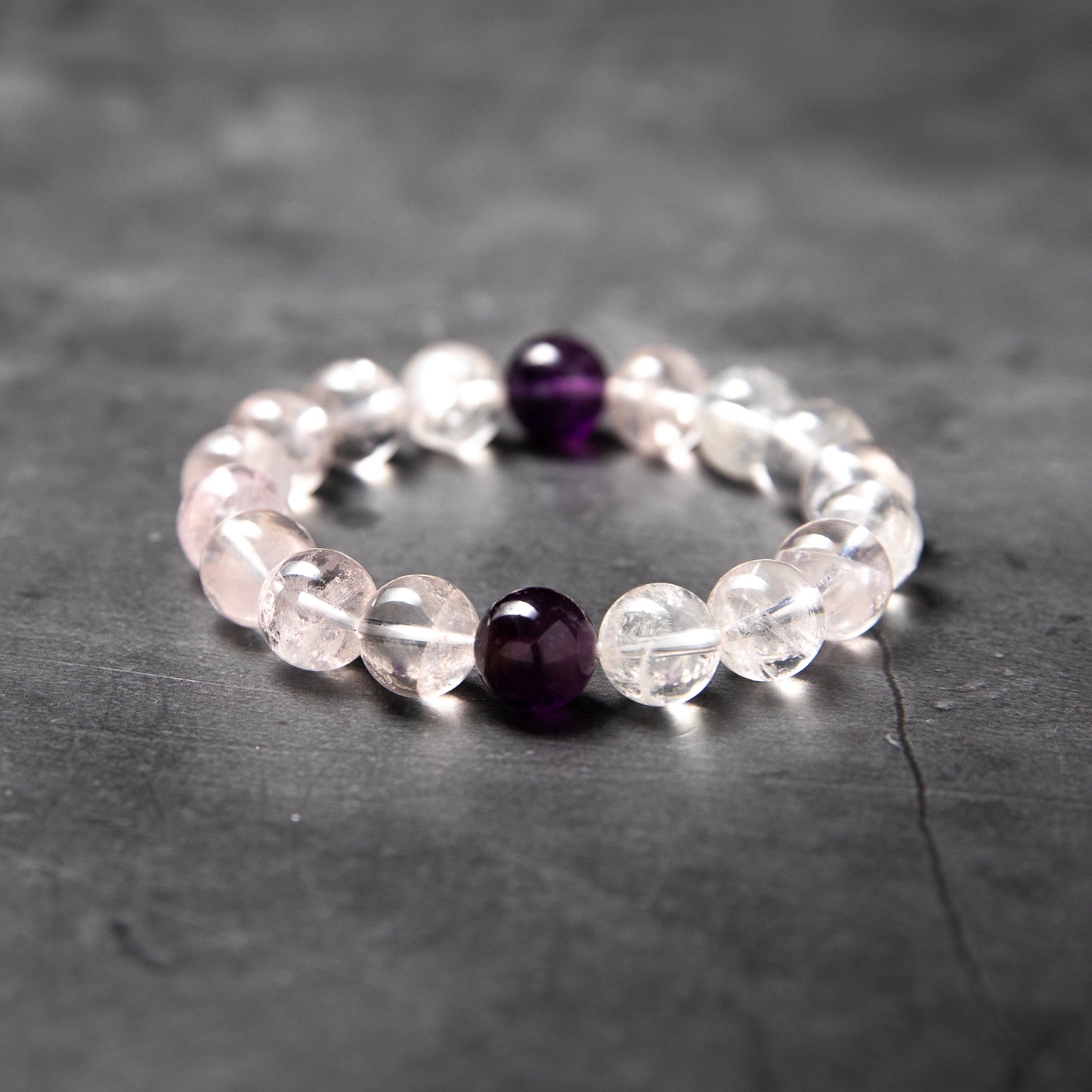 Beaded bracelet with clear and purple beads on a dark surface