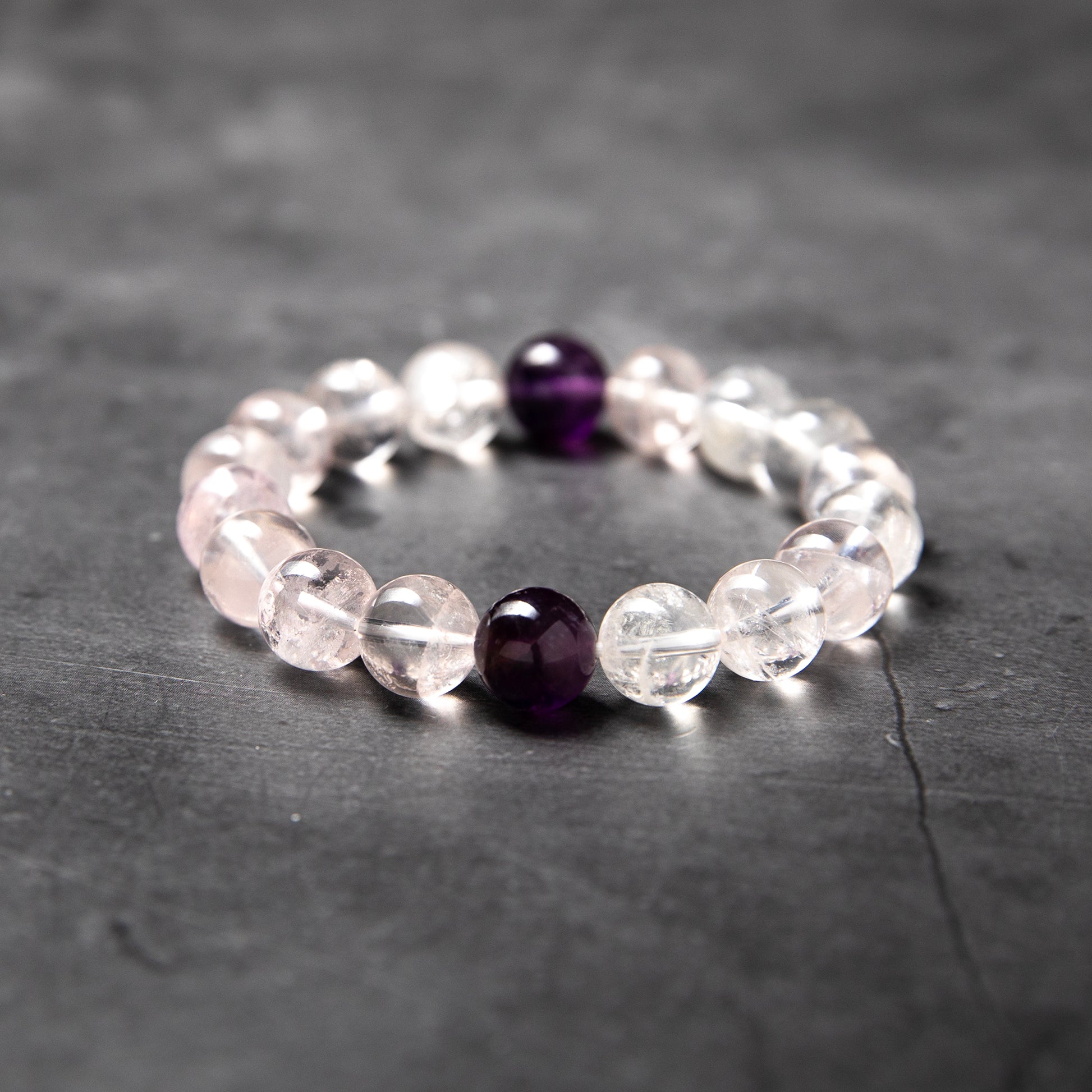 Beaded bracelet with clear and purple beads on a dark surface