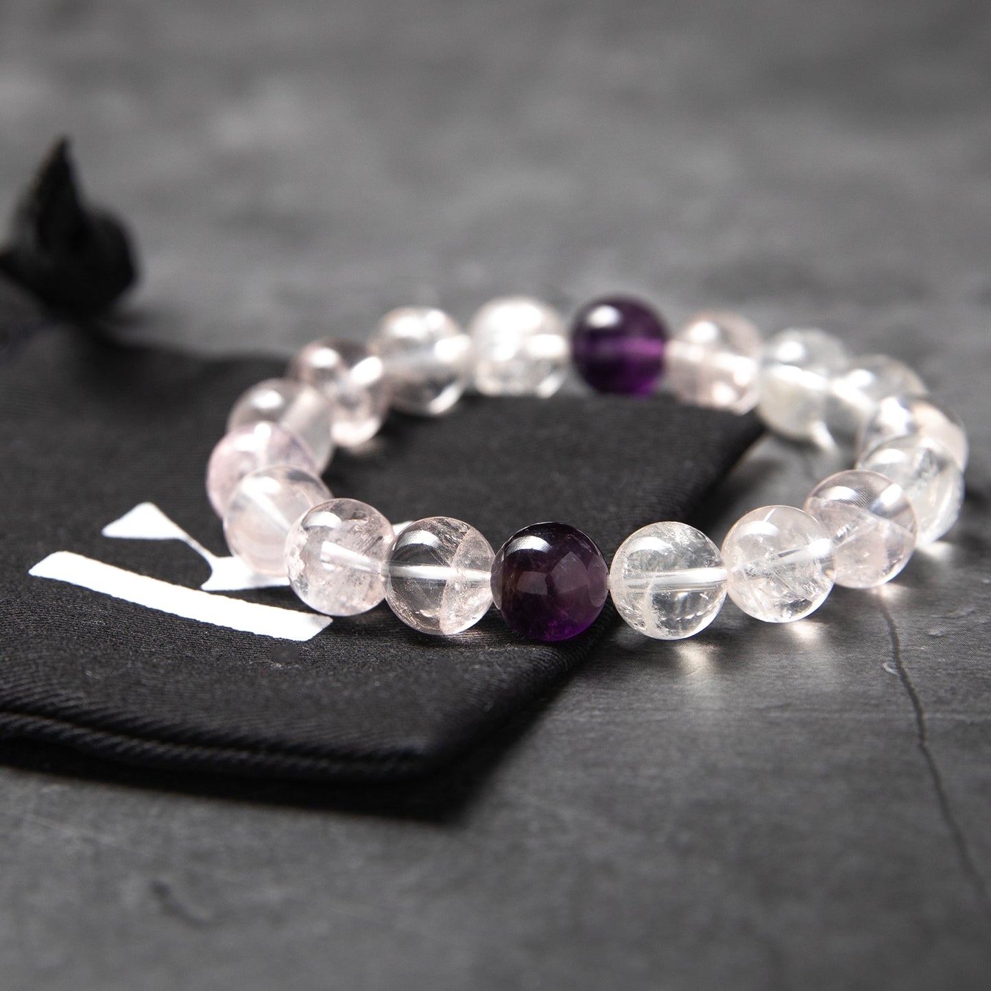 Beaded bracelet with clear and purple beads on a dark surface