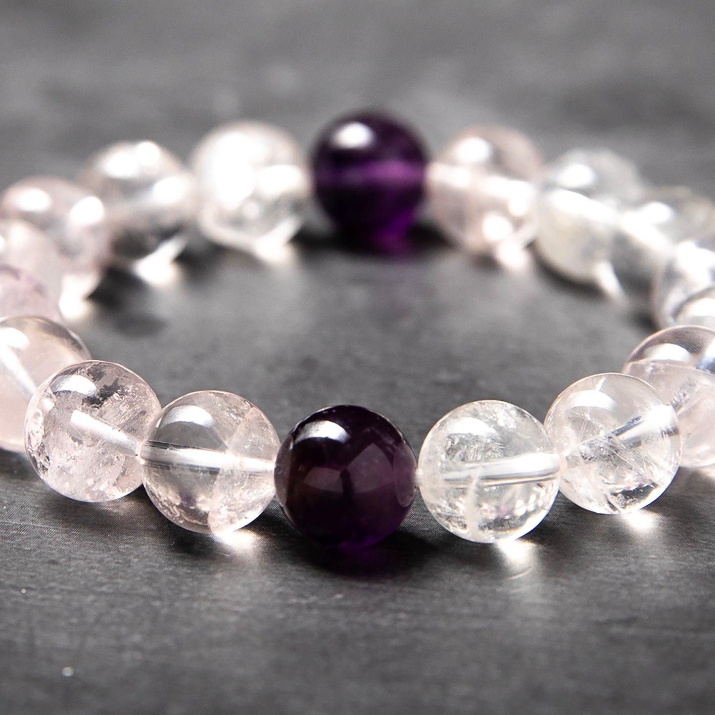 Beaded bracelet with clear and purple beads on a dark surface