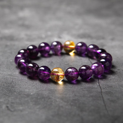 Beaded bracelet with purple and gold beads on a gray surface