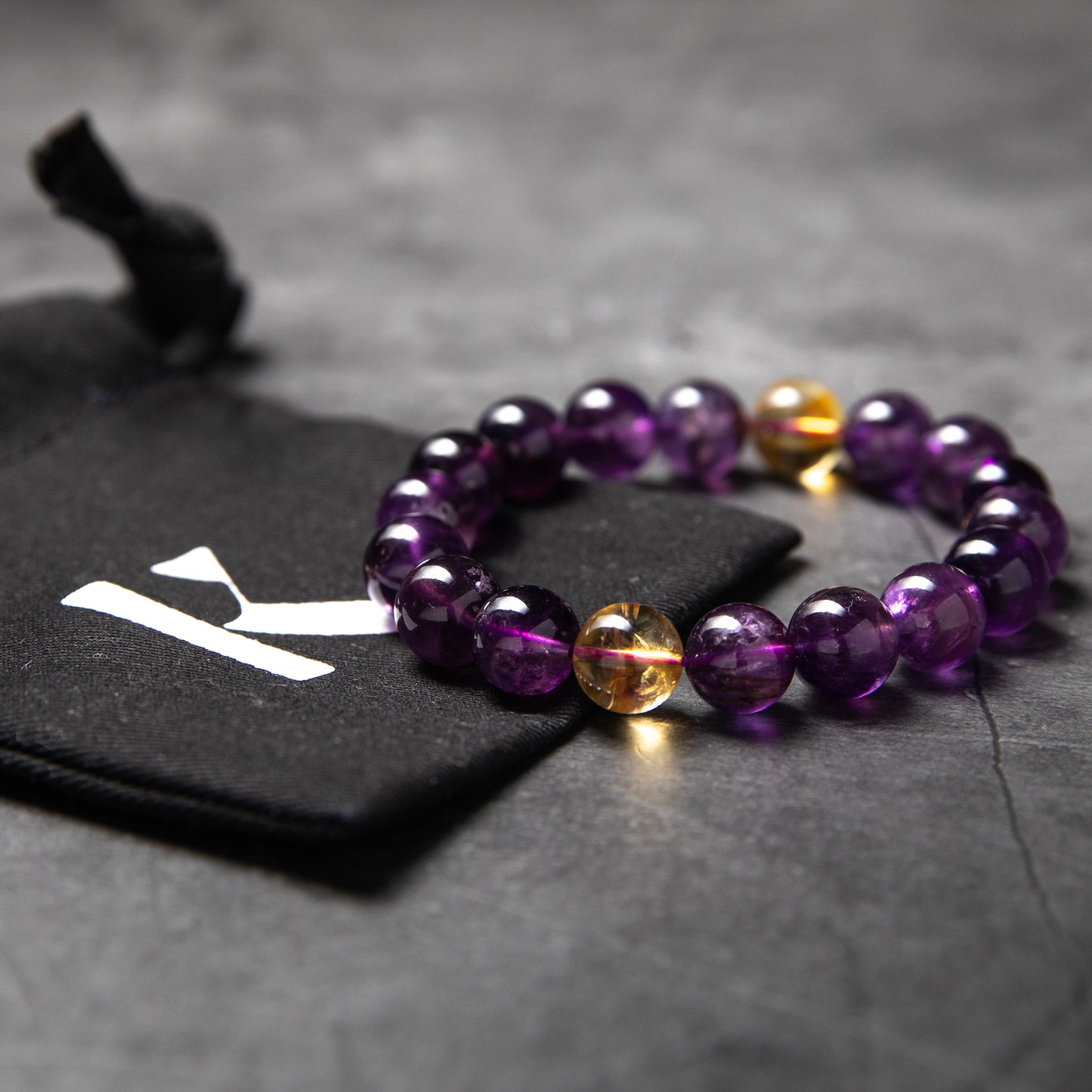 Purple beaded bracelet with a gold accent on a dark surface