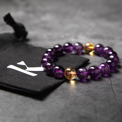 Purple beaded bracelet with a gold accent on a dark surface
