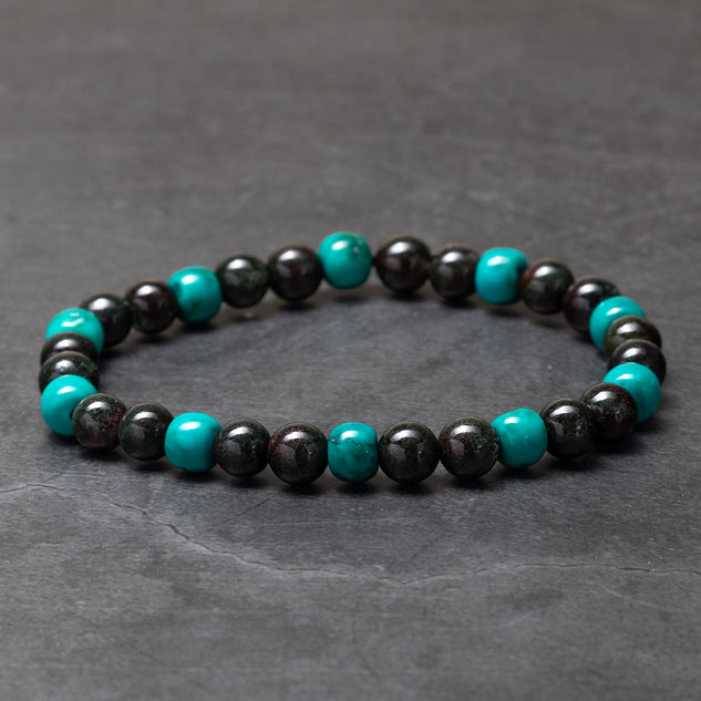 Beaded bracelet with black and turquoise beads on a dark gray background