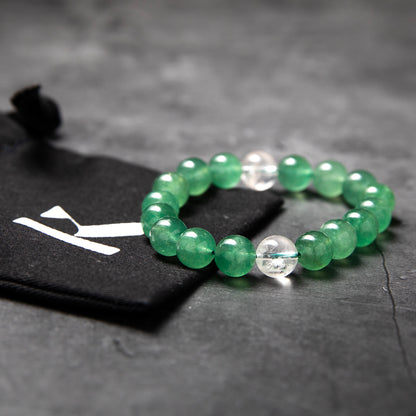 Green beaded bracelet on a dark surface with a blurred background
