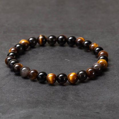Beaded bracelet with black, brown, and gold beads on a dark gray background