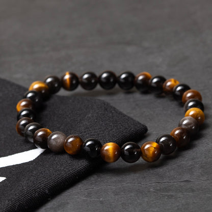 Beaded bracelet with black, brown, and gray beads on a dark surface