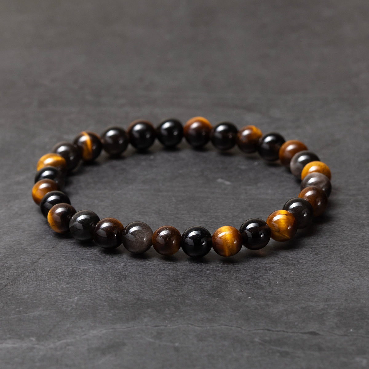 Beaded bracelet with black, brown, and gold beads on a dark gray background