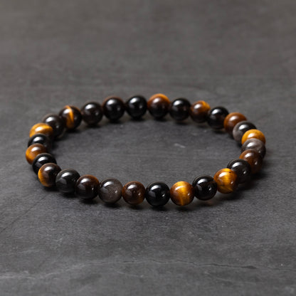 Beaded bracelet with black, brown, and gold beads on a dark gray background