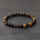 Beaded bracelet with black, brown, and gold beads on a dark gray background
